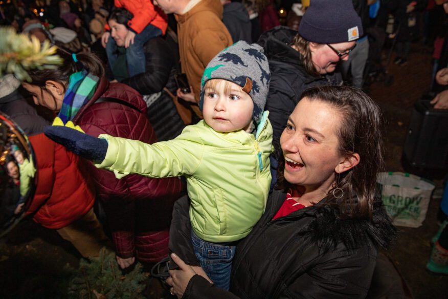 A young child reaches out while being held in the crowd at Salem’s 2025 Tree Lighting.