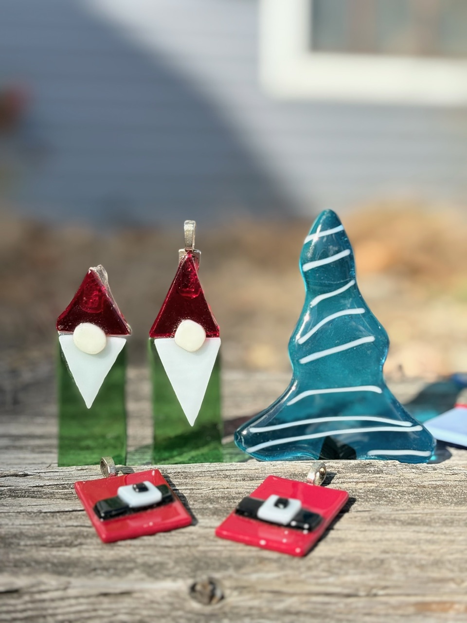 Fused glass gnome ornaments, a blue glass tree, and Santa-belt pendants from North Shore Glass School